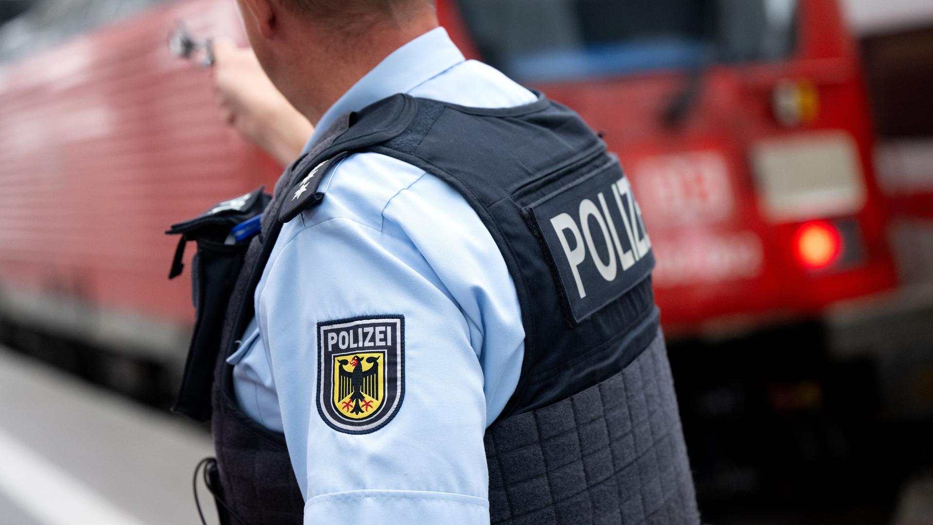 Ein Bundespolizist steht in München an einem Bahnsteig vor einem Zug der Deutschen Bahn.