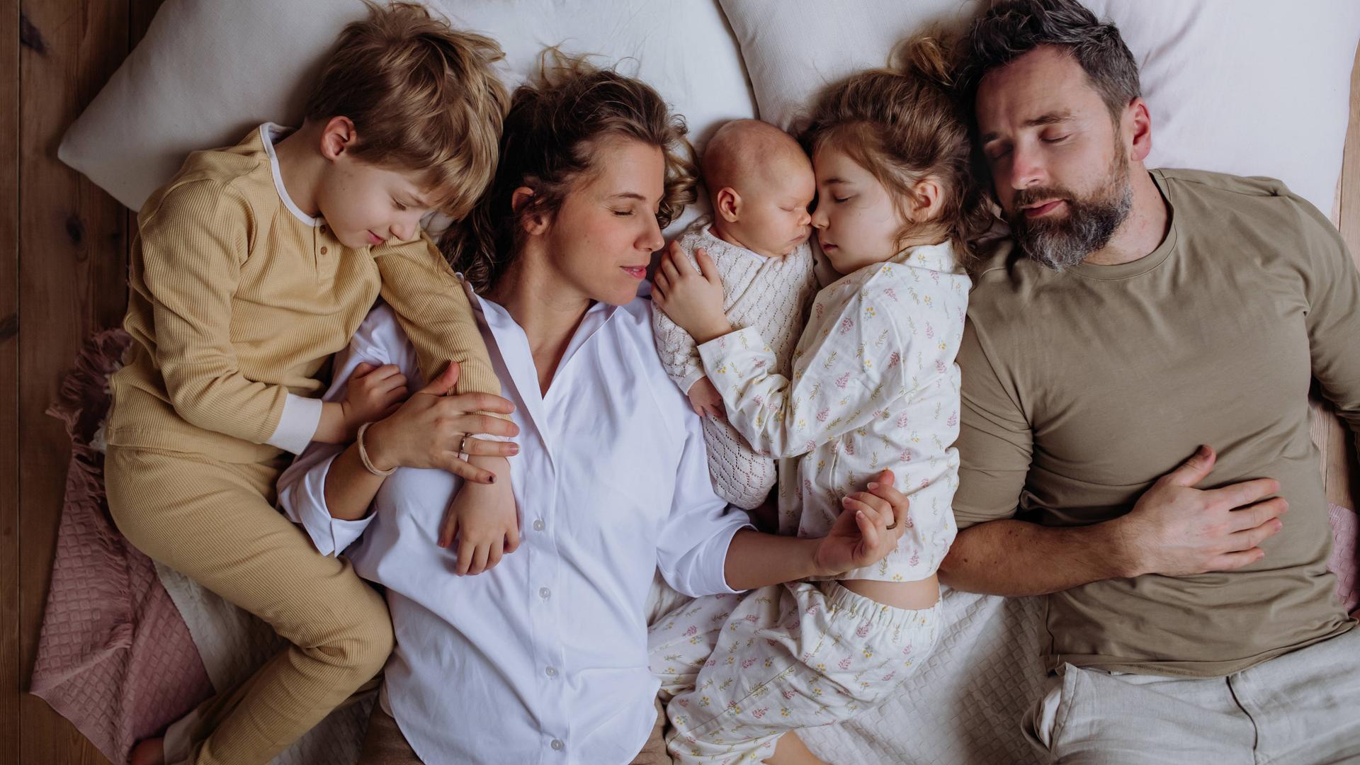 Eine Familie liegt gemeinsam in einem Bett und schläft. Eine Familie liegt gemeinsam in einem Bett und schläft.