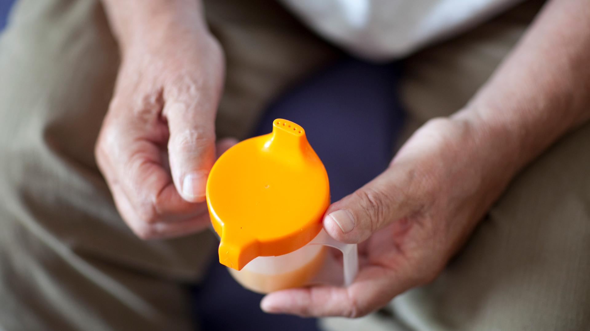 Hände halten eine Schnabeltasse.