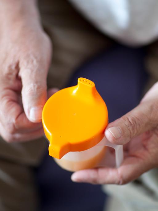 Hände halten eine Schnabeltasse.