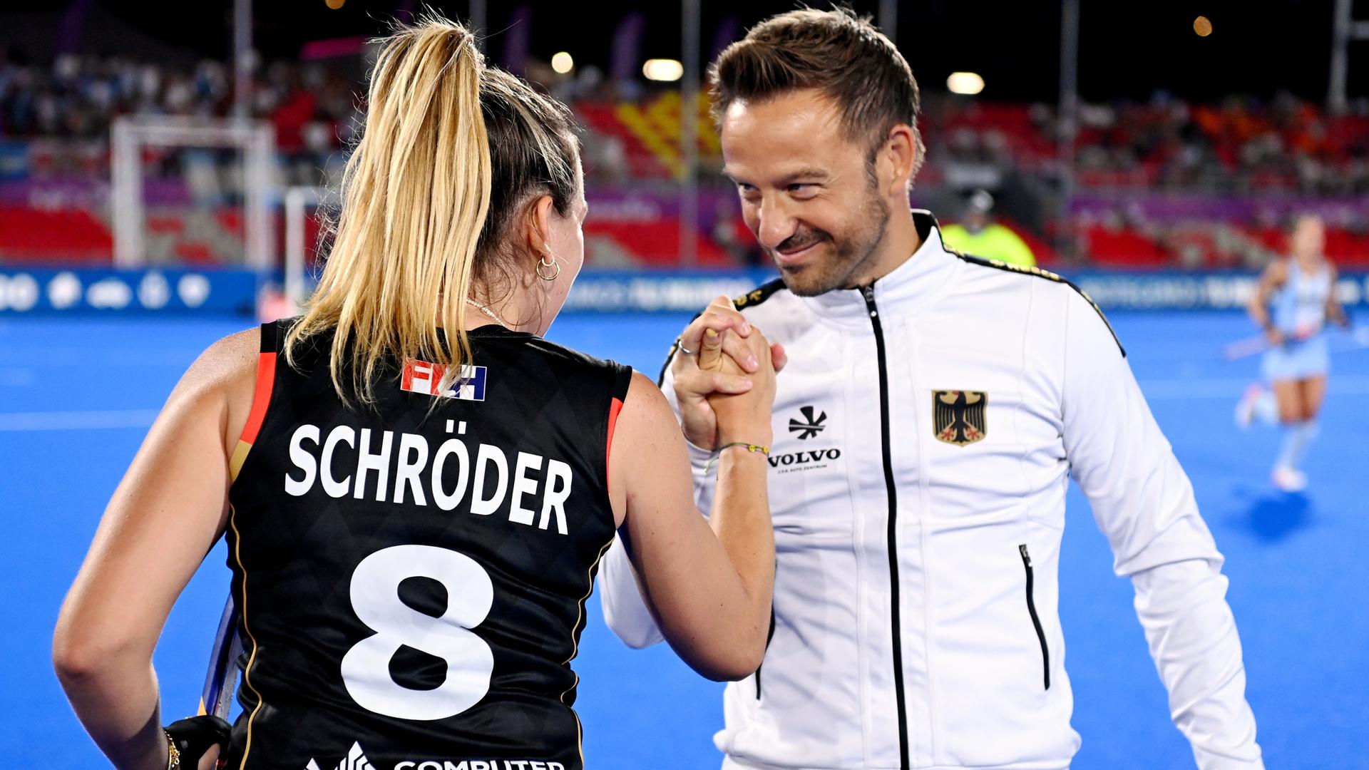 Hockey-Spielerin Anne Schröder und ihr Trainer Valentin Altenburg klatschen sich ab und schauen sich in die Augen. 