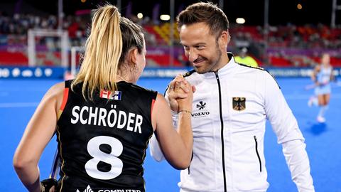 Hockey-Spielerin Anne Schröder und ihr Trainer Valentin Altenburg klatschen sich ab und schauen sich in die Augen. 