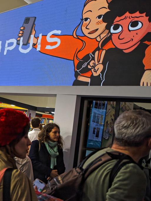 Messestände und Besucherinnen und Besucher beim Comic-Festival in Angoulême 2025. Auf einem Werbebanner sind zwei Comic-Figuren zu sehen