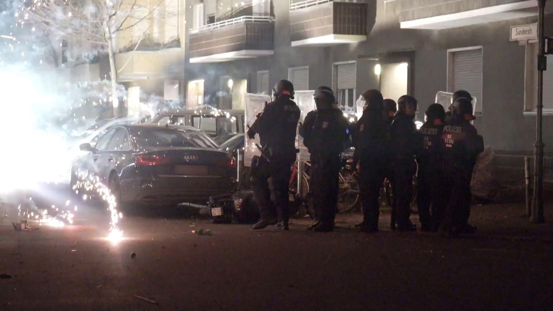 ベルリン・ノイケルンで爆発する花火の後ろに立つ警察官