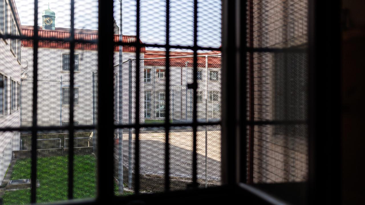Blick aus einer Gefangenenzelle in der Justizvollzugsanstalt Nürnberg. Der Blick durch das vergitterte Fenster zeigt den Innenhof des Gefängnisses. 
