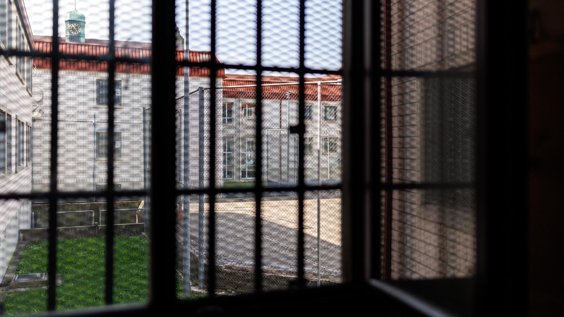 Blick aus einer Gefangenenzelle in der Justizvollzugsanstalt Nürnberg. Der Blick durch das vergitterte Fenster zeigt den Innenhof des Gefängnisses. 