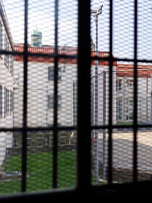 Blick aus einer Gefangenenzelle in der Justizvollzugsanstalt Nürnberg. Der Blick durch das vergitterte Fenster zeigt den Innenhof des Gefängnisses. 