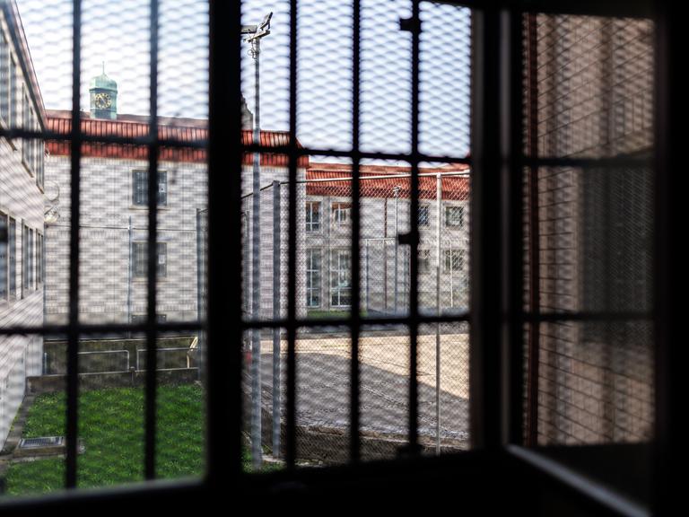 Blick aus einer Gefangenenzelle in der Justizvollzugsanstalt Nürnberg. Der Blick durch das vergitterte Fenster zeigt den Innenhof des Gefängnisses. 