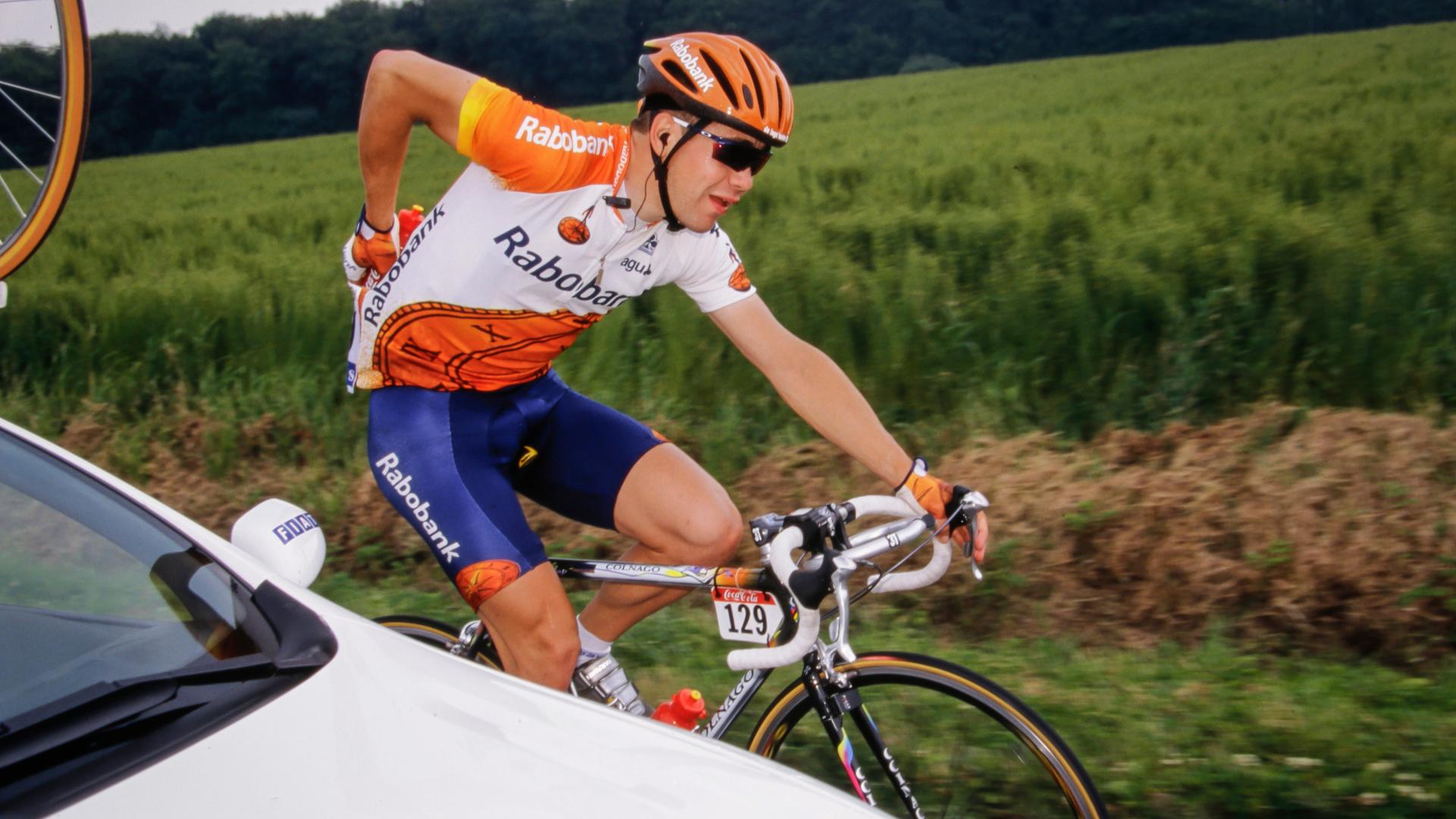 Leon van Bon nimmt aus einem Begleitwagen Wasserflaschen entgegen und steckt sie in sein Trikot.