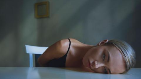 Der Kopf einer erschöpften Frau liegt auf einer Tischplatte (Symbolfoto)