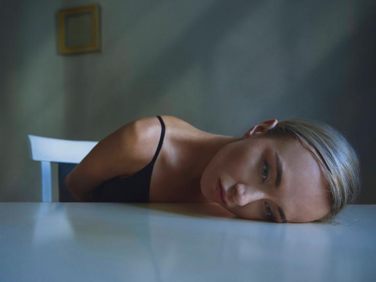 Der Kopf einer erschöpften Frau liegt auf einer Tischplatte (Symbolfoto)