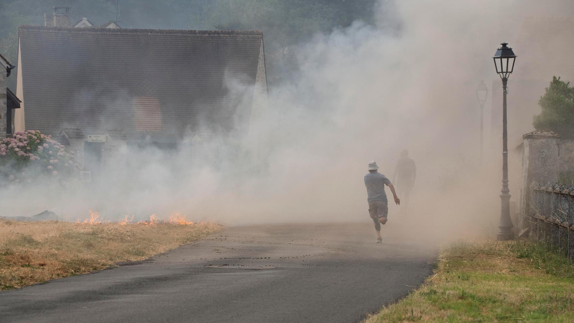 Eine Person läuft los, um Hilfe zu holen, nachdem in der Nähe von Wohnhäusern in Noisy-sur-École (Frankreich) ein Feld in Brand geraten ist, während ein Großbrand den Wald von Fontainebleau – das größte Waldgebiet der Region Île-de-France – erfasst. Eine Person läuft los, um Hilfe zu holen, nachdem in der Nähe von Wohnhäusern in Noisy-sur-École (Frankreich) ein Feld in Brand geraten ist, während ein Großbrand den Wald von Fontainebleau – das größte Waldgebiet der Region Île-de-France – erfasst.