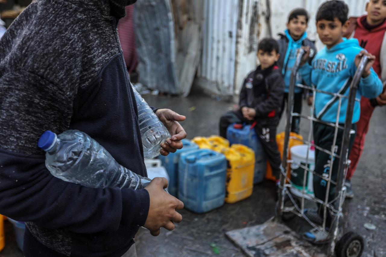 Palästinenser trägt Trinkwasser in Wasserflaschen, das die Hilfsorganisation UNRWA nach Rafah im Gazastreifen geliefert hat.