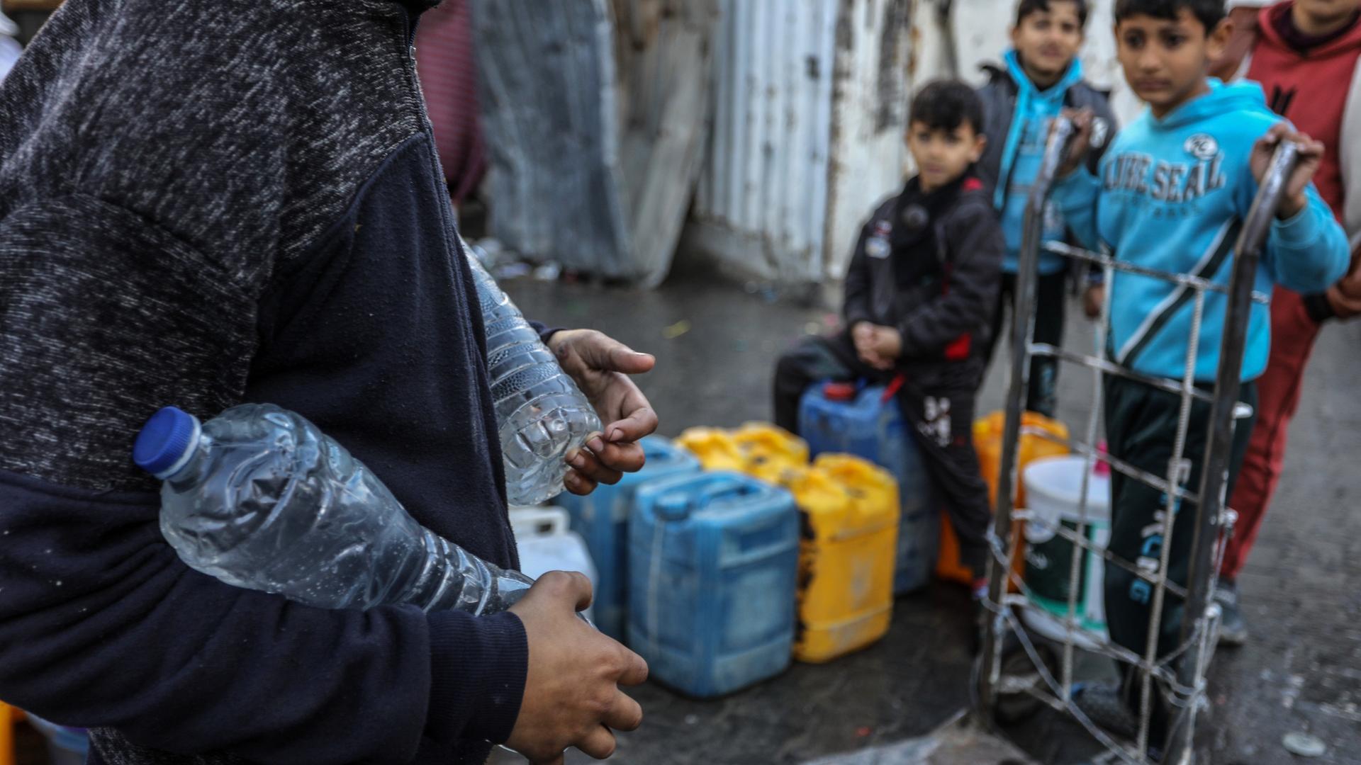 Ein Palästinenser trägt Trinkwasser in Wasserflaschen, das eine Hilfsorganisation nach Rafah im Gazastreifen geliefert hat.