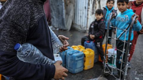 Ein Palästinenser trägt Trinkwasser in Wasserflaschen, das eine Hilfsorganisation nach Rafah im Gazastreifen geliefert hat.