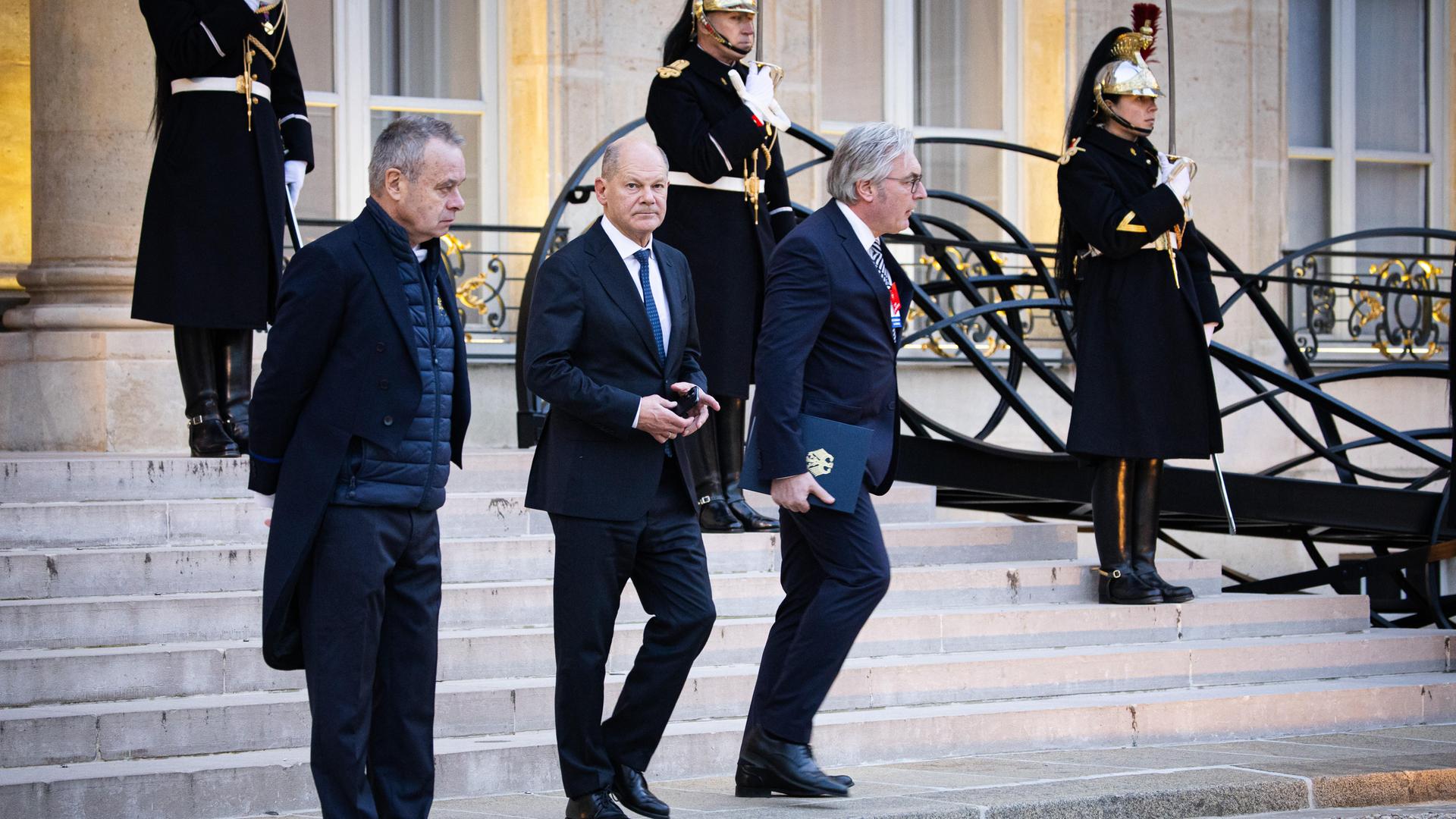 Bundeskanzler Olaf Scholz ist dabei, den Elysée- Palast in Paris zu verlassen. Im Hintergrund steht Wachpersonal vor den Treppen des Präsidentenpalastes.