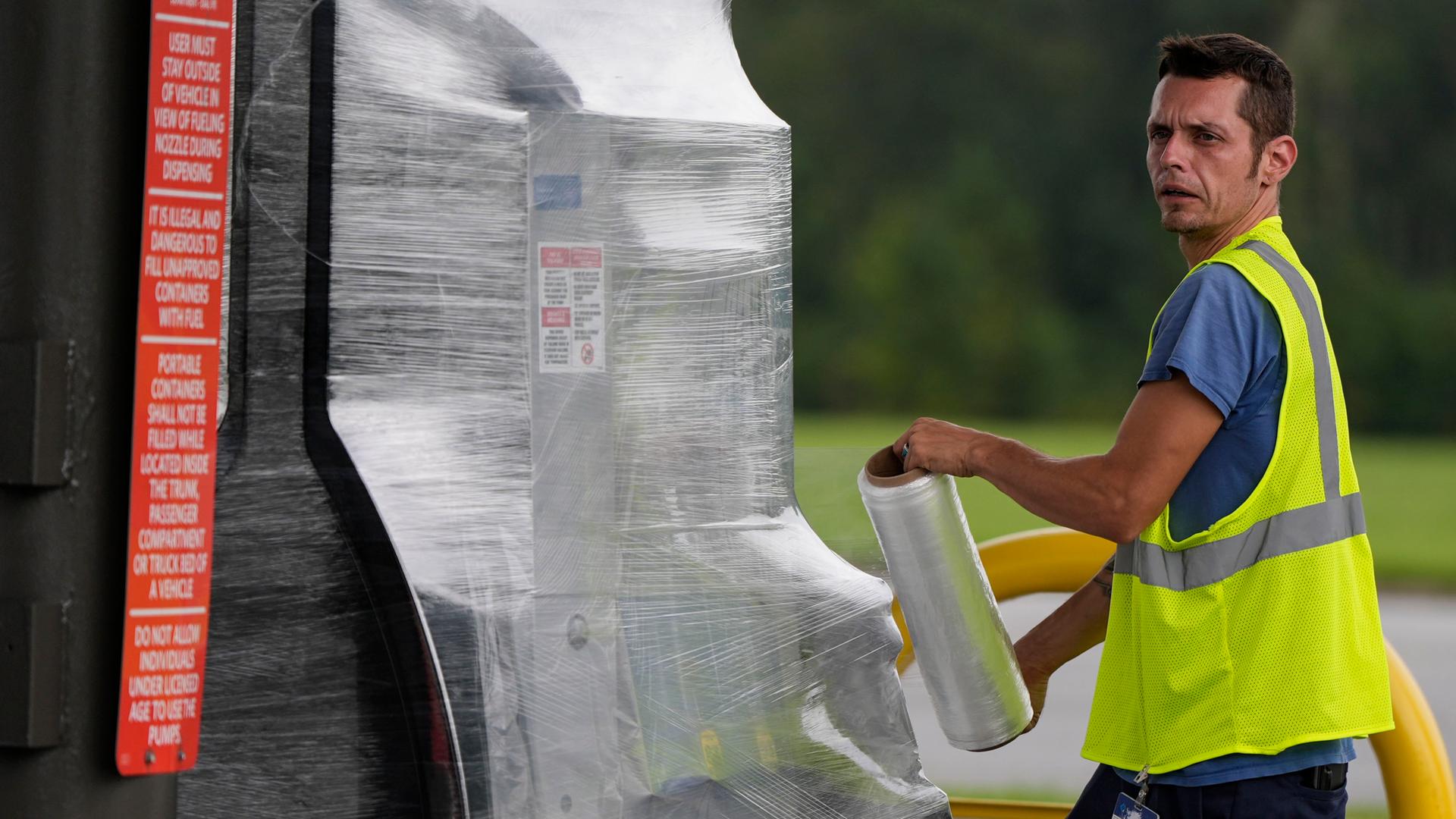 Ein Mitarbeiter einer Tankstelle wickelt Folie um eine Zapfsäule, um Schäden durch den Hurrikan Helene zu verhindern. Aufnahme aus Valdosta im US-Bundesstaat Georgia vom 26.09.2024.