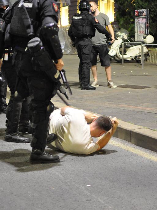 Belgrad am 13. August: Ein junger Mann liegt am Boden, hinter ihm stehen zwei bewaffnete Polizisten