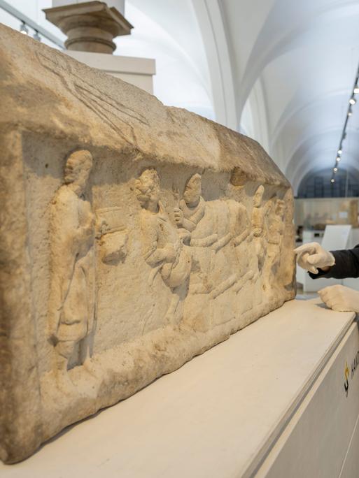 Ein großer Steinblock mit eingemeißelten Figuren: Die Augsburger Grabreliefs zeigen Motive aus dem Wein- und Textilhandel. 
