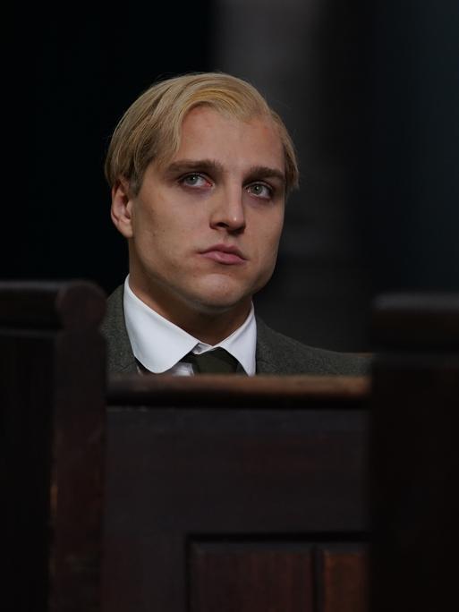 Szene aus dem Film "Bonhoeffer: Pastor. Spy. Assassin.": Ein junger Mann mit halblangem blondem Haar sitzt in einer Kirchenbank.