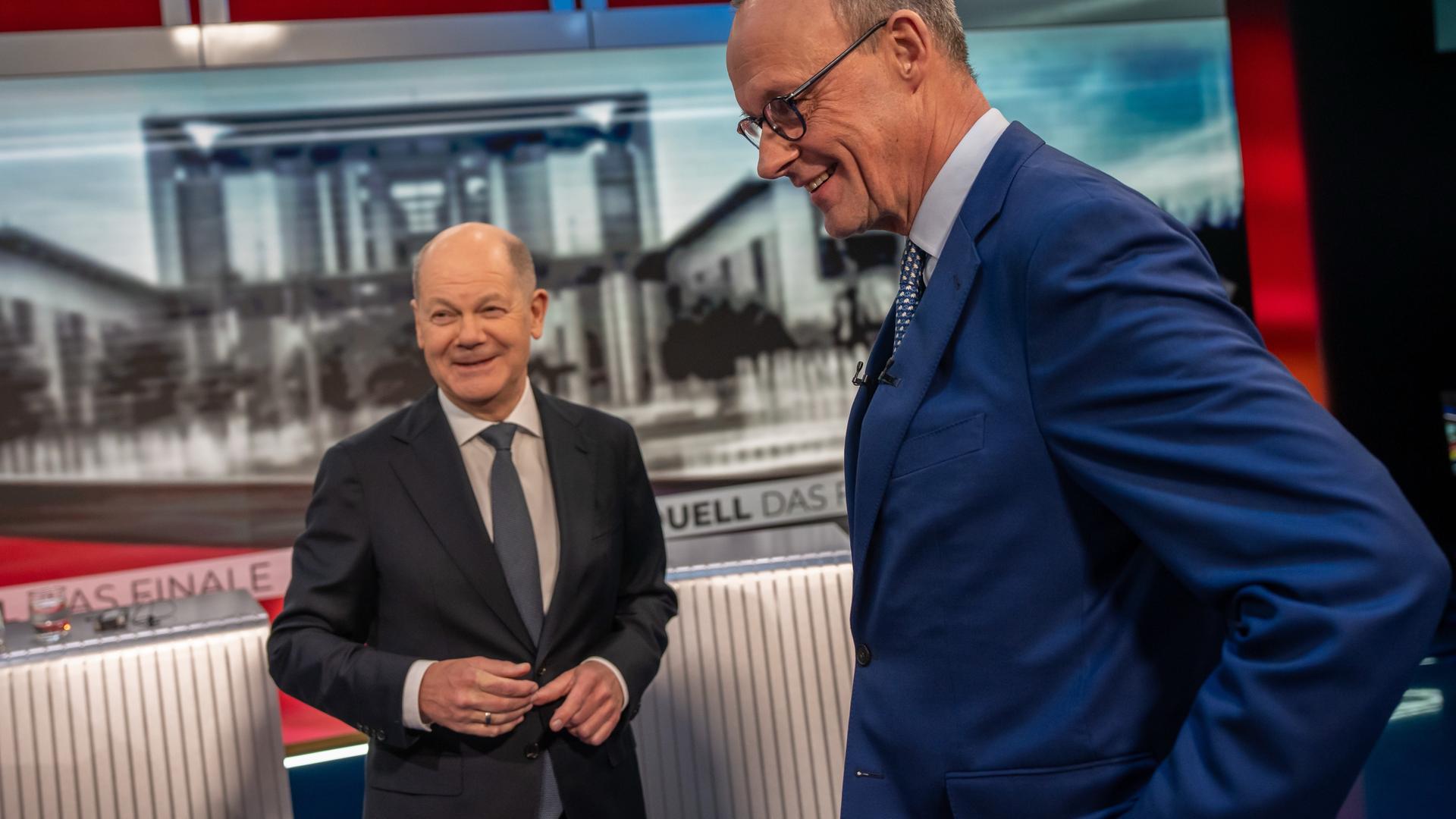 Zwei Männer in Anzügen stehen in einem Fernsehstudio: Bundeskanzler Olaf Scholz und CDU-Spitzenkandidat Friedrich Merz. 