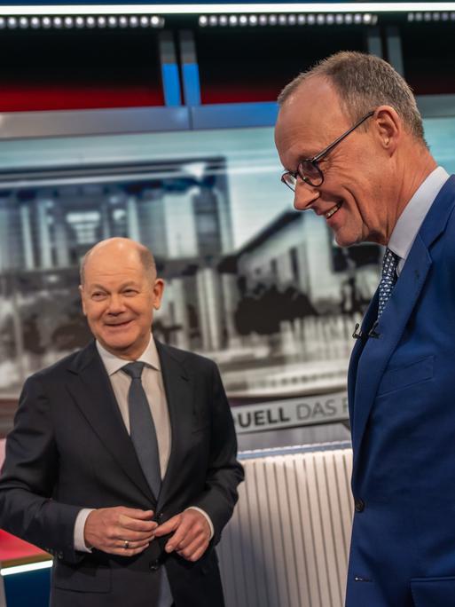 Zwei Männer in Anzügen stehen in einem Fernsehstudio: Bundeskanzler Olaf Scholz und CDU-Spitzenkandidat Friedrich Merz. 