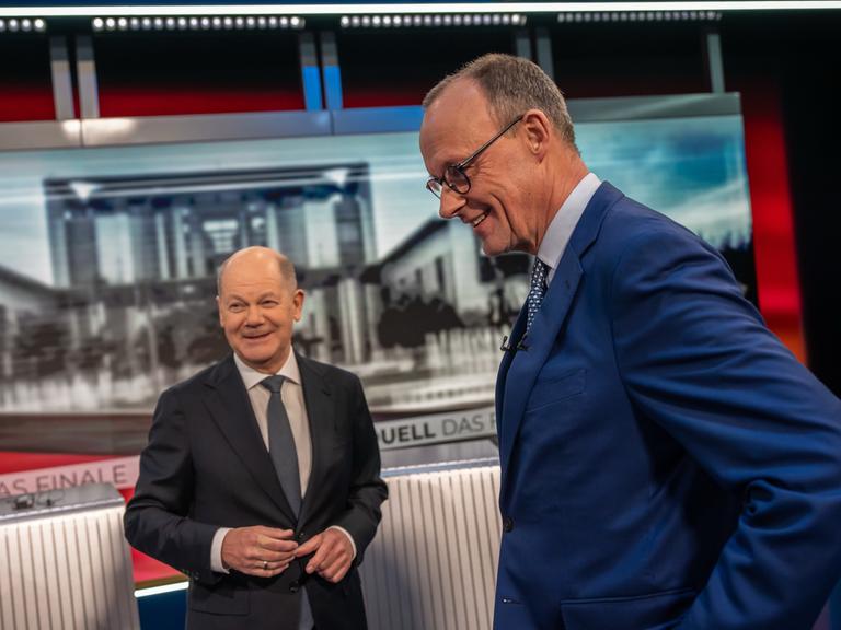 Zwei Männer in Anzügen stehen in einem Fernsehstudio: Bundeskanzler Olaf Scholz und CDU-Spitzenkandidat Friedrich Merz. 