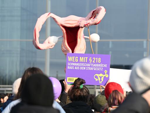 Mit einem überdimensionalen Uterus demonstrieren Menschen für die Legalisierung von Schwangerschaftsabbrüchen. Ein Plakat trägt die Aufschrift "Weg mit § 218".
