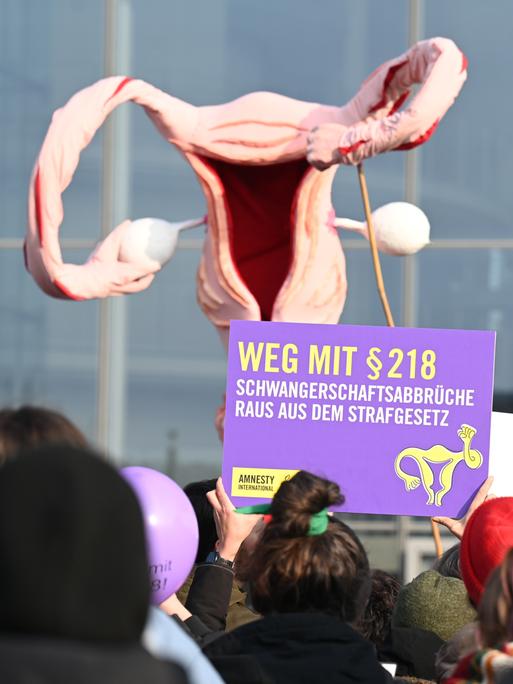 Mit einem überdimensionalen Uterus demonstrieren Menschen für die Legalisierung von Schwangerschaftsabbrüchen. Ein Plakat trägt die Aufschrift "Weg mit § 218".