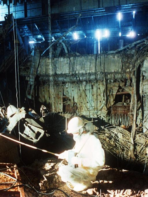 Eine historische Aufnahme von 1986 zeigt, wie zwei Helfer in weißer Schutzkleidung in den Trümmern des zerstörten Atomkraftwerks in Tschernobyl aufräumen. 