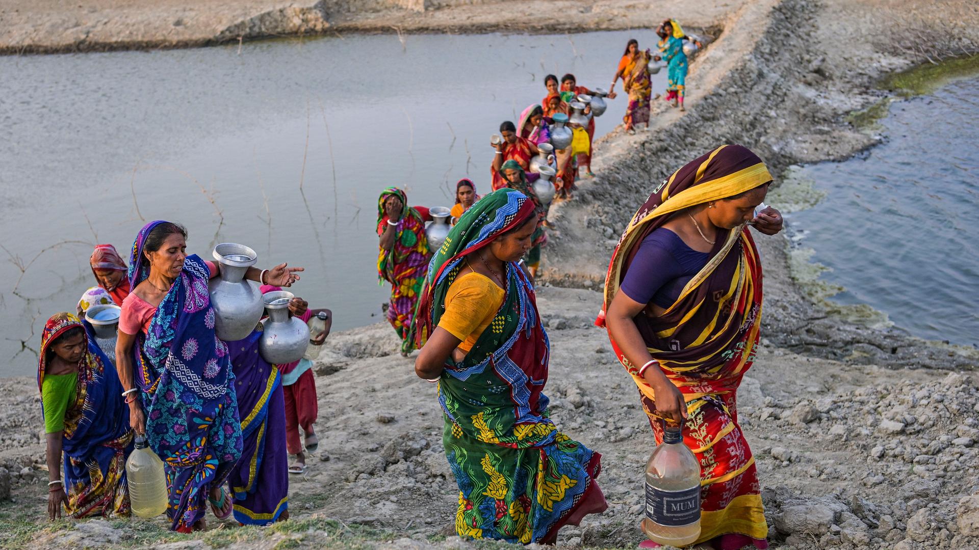 Mehrere Frauen tragen Wasser aus einem Brunnen.