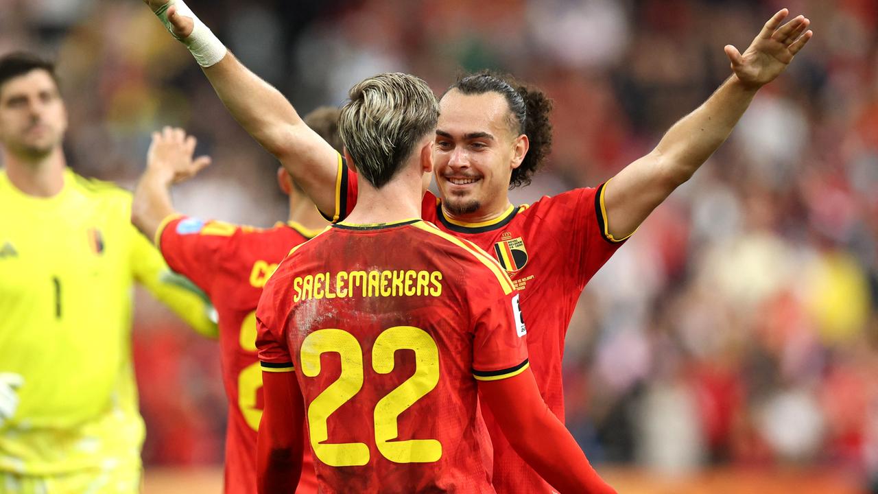 Der belgische Fußballer Arthur Theate streckt seine Arme in die Luft und feiert mit seinem Teamkollegen Alexis Saelemaekers 