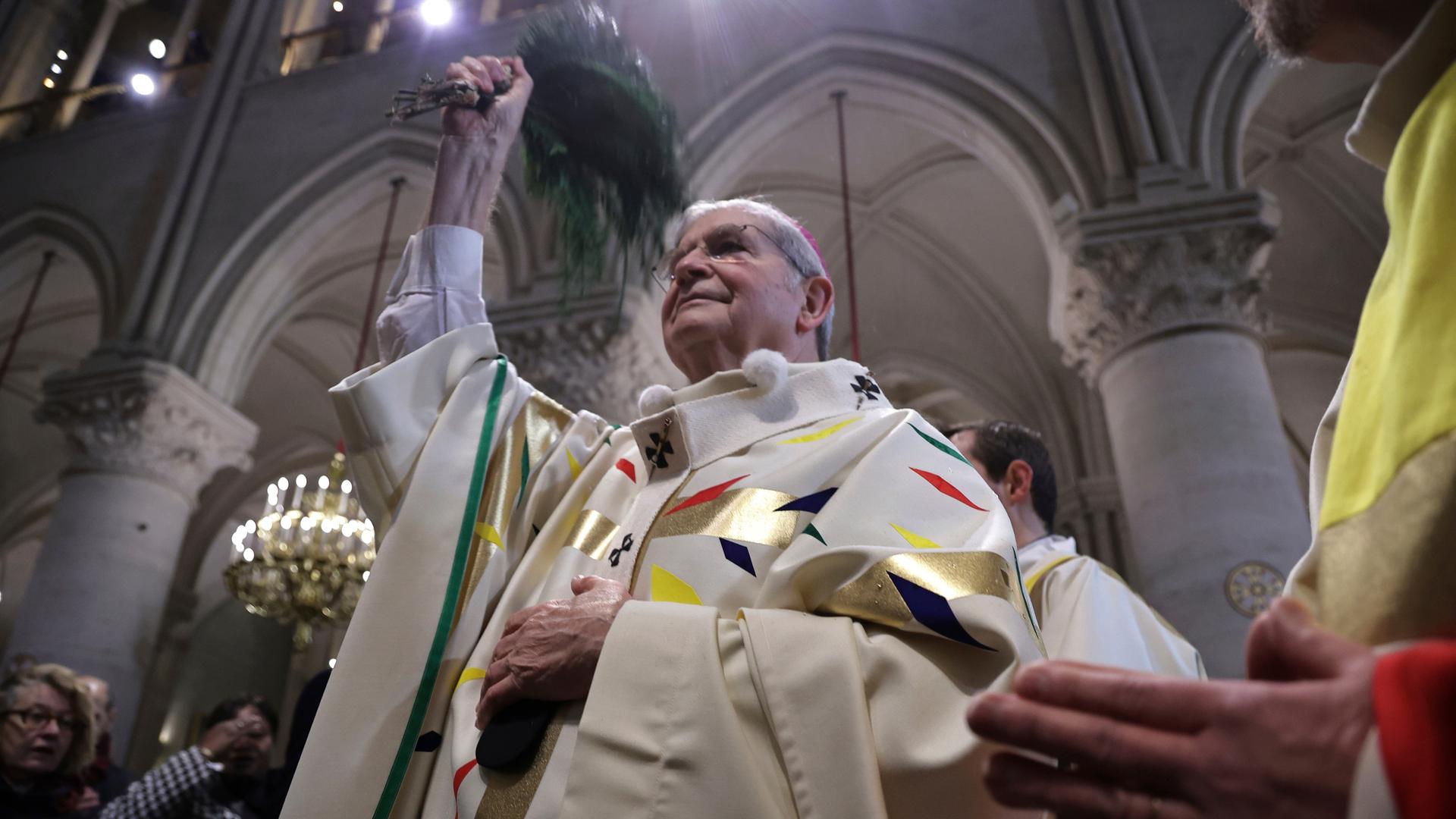 Der Pariser Erzbischof Laurent Ulrich bei der Eröffnungsmesse in der Kathedrale Notre Dame in Paris. Er ist von unten fotografiert, sodass man das Deckengewölbe der Kirche sieht.