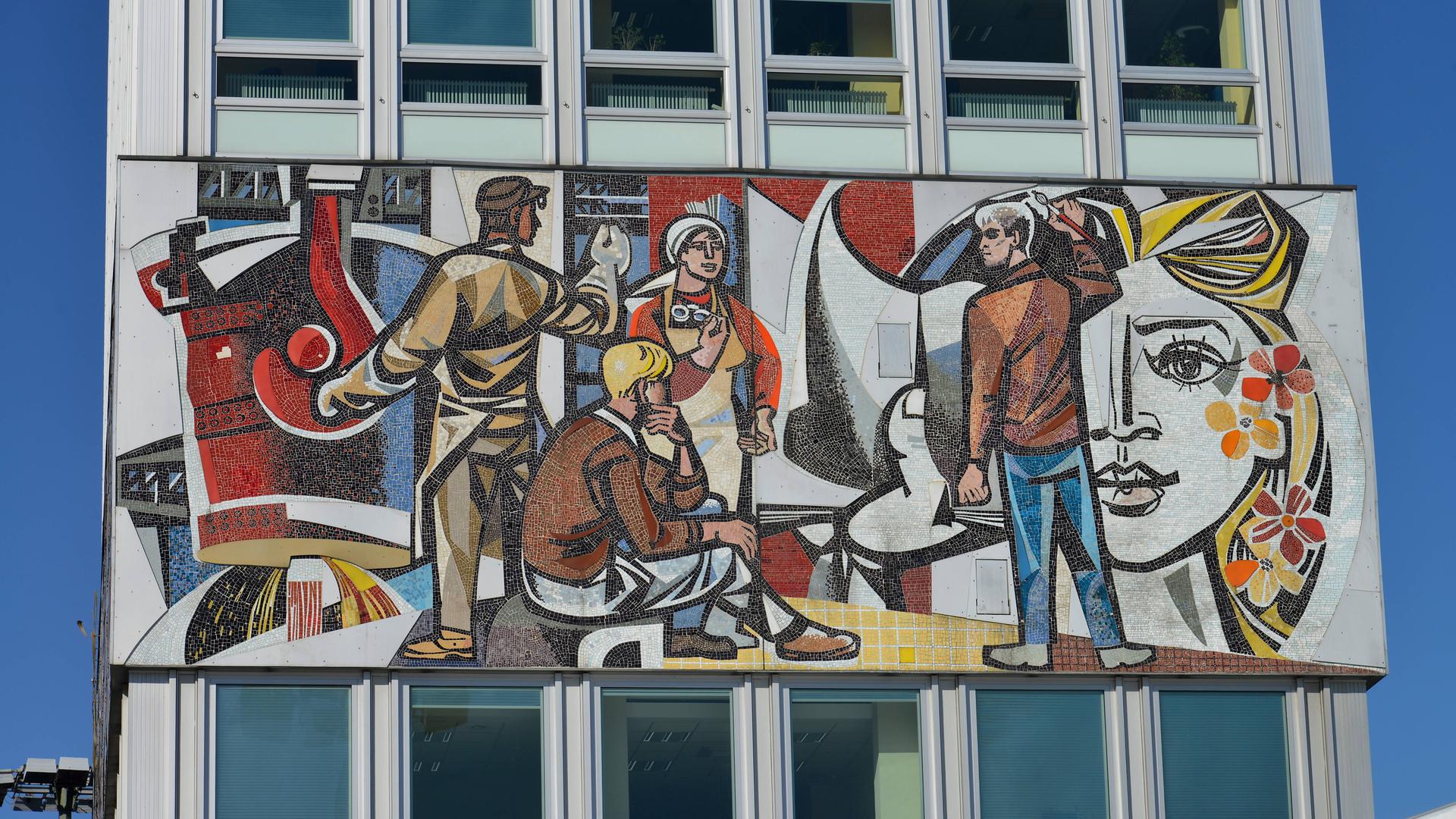 Auf einem Wandgemälde sind Werktätige der DDR abgebildet. 
