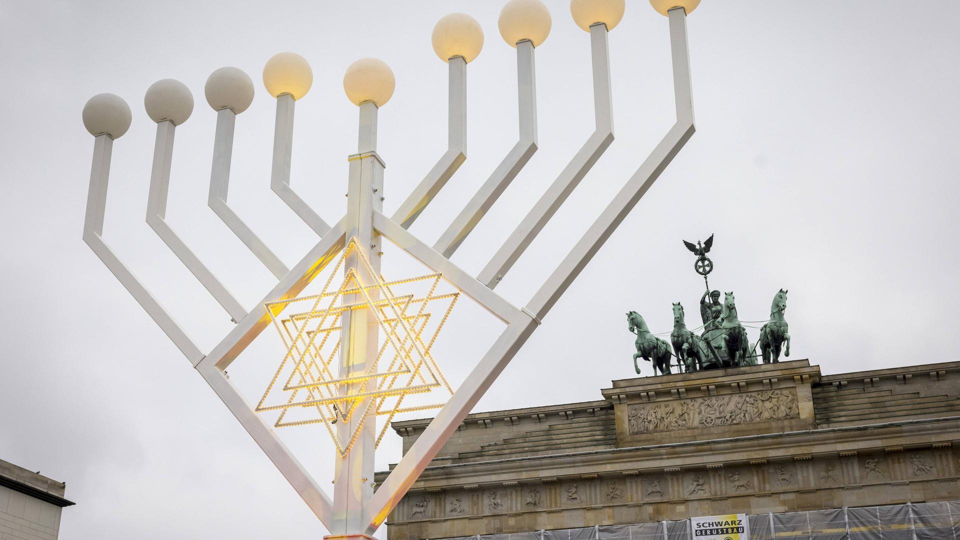 Ein achtarmiger Leuchter mit einem Davidstern im Zentrum steht vor dem Brandenburger Tor.