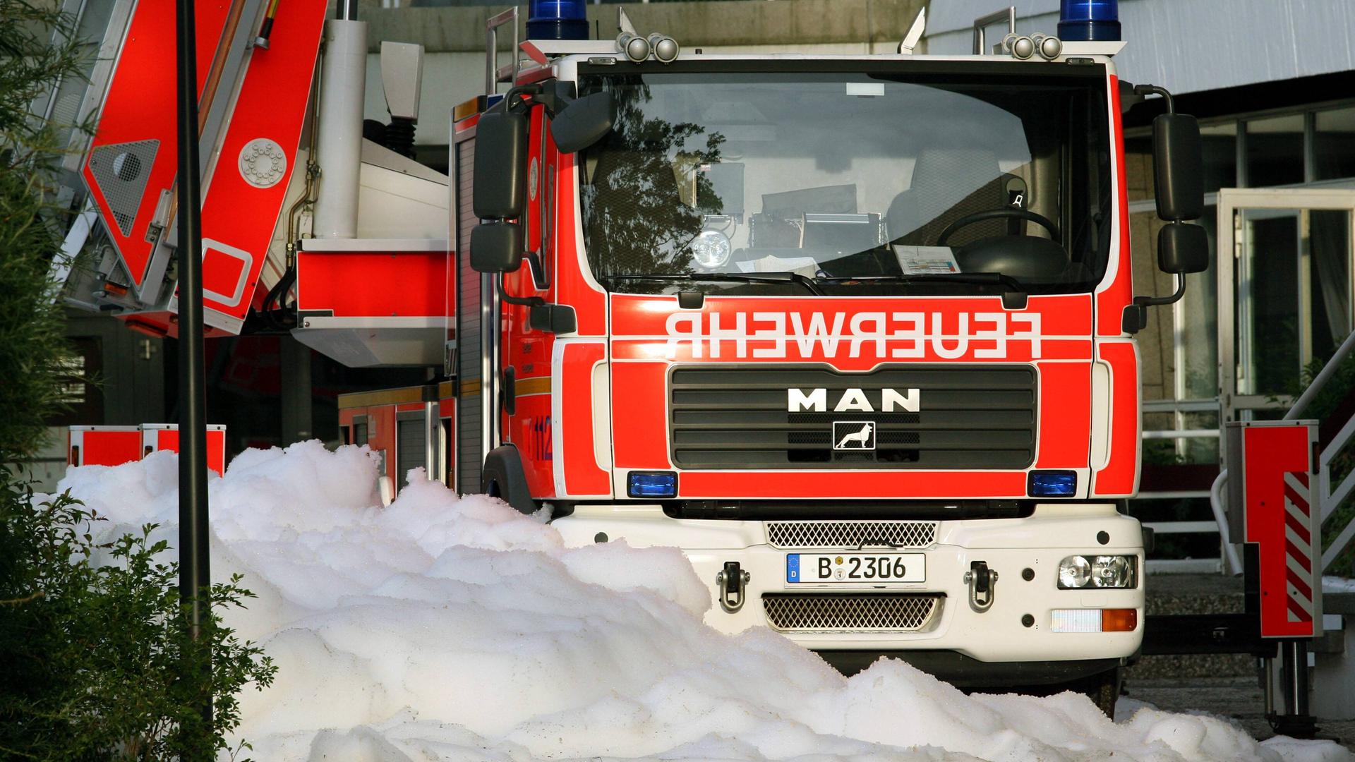 Ein Feuerwehrauto der Berliner Feuerwehr. Davor Löschschaum auf dem Boden.