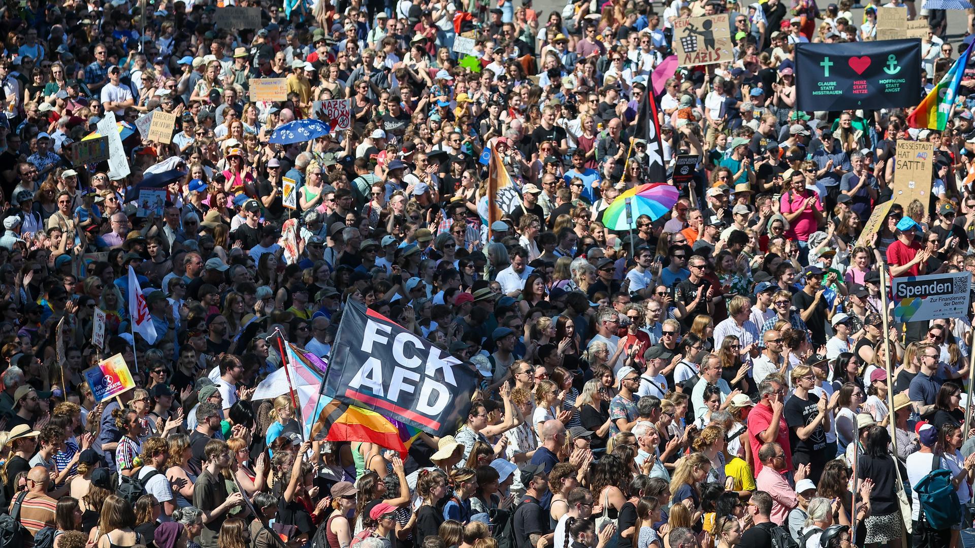 Zahlreiche Teilnehmer der Kundgebung "Hand in Hand für Demokratie und Menschenrechte" gegen Rechtsextremismus stehen auf dem Leuschnerplatz in Leipzig. Auf einer Fahne ist "FCK AFD" zu lesen.