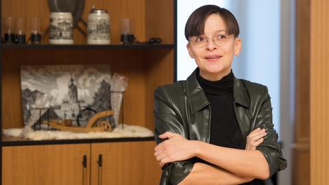 Die Künstlerin Henrike Naumann vor einem Regal mit deutschen Devotialien. 