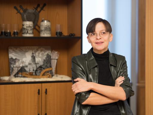 Die Künstlerin Henrike Naumann vor einem Regal mit deutschen Devotialien. 