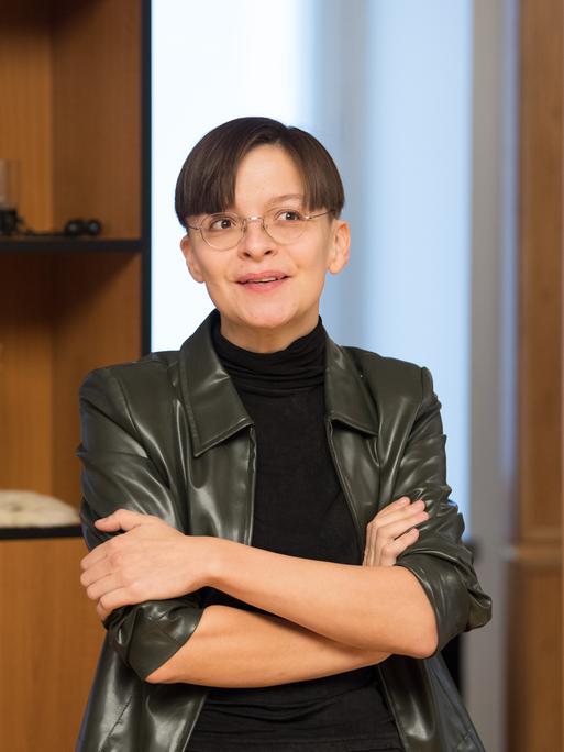 Die Künstlerin Henrike Naumann vor einem Regal mit deutschen Devotialien. 