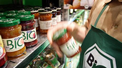 Auf einem Messestand der Grünen Woche 2007 stehen Biolebensmittel in einem Regal. Einer Person davor trägt eine grüne Schürze mit einem Aufdruck "Bio nach EG-Öko-Verordnung".