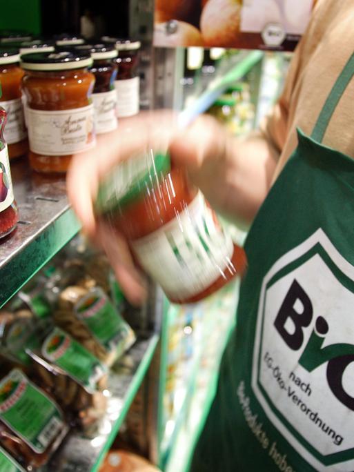Auf einem Messestand der Grünen Woche 2007 stehen Biolebensmittel in einem Regal. Einer Person davor trägt eine grüne Schürze mit einem Aufdruck "Bio nach EG-Öko-Verordnung".