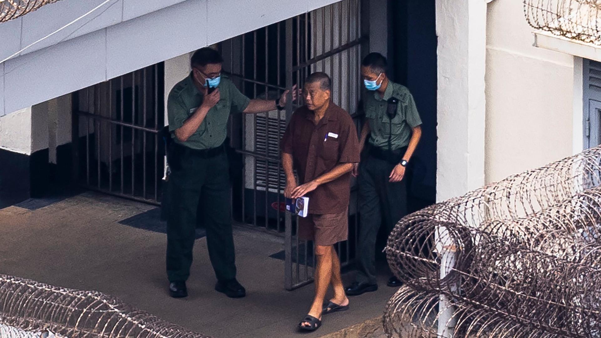 Jimmy Lai geht begleitet von zwei Wachmännern aus dem Stanley Gefängnis in Hongkong. Jimmy Lai geht begleitet von zwei Wachmännern aus dem Stanley Gefängnis in Hongkong.