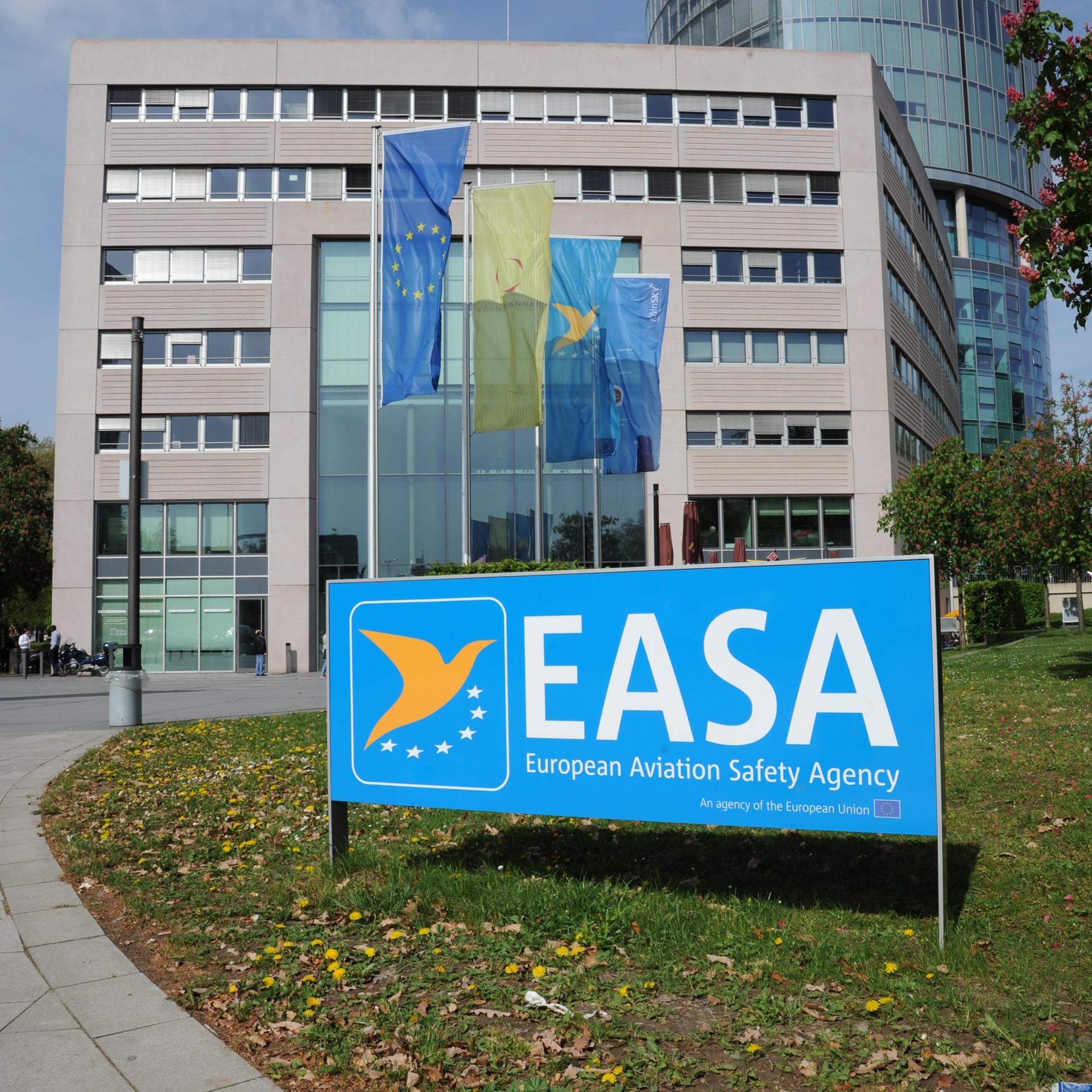 Zu sehen ist ein Schild der Europäischen Agentur für Flugsicherheit, im Hintergrund das Gebäude in Köln.