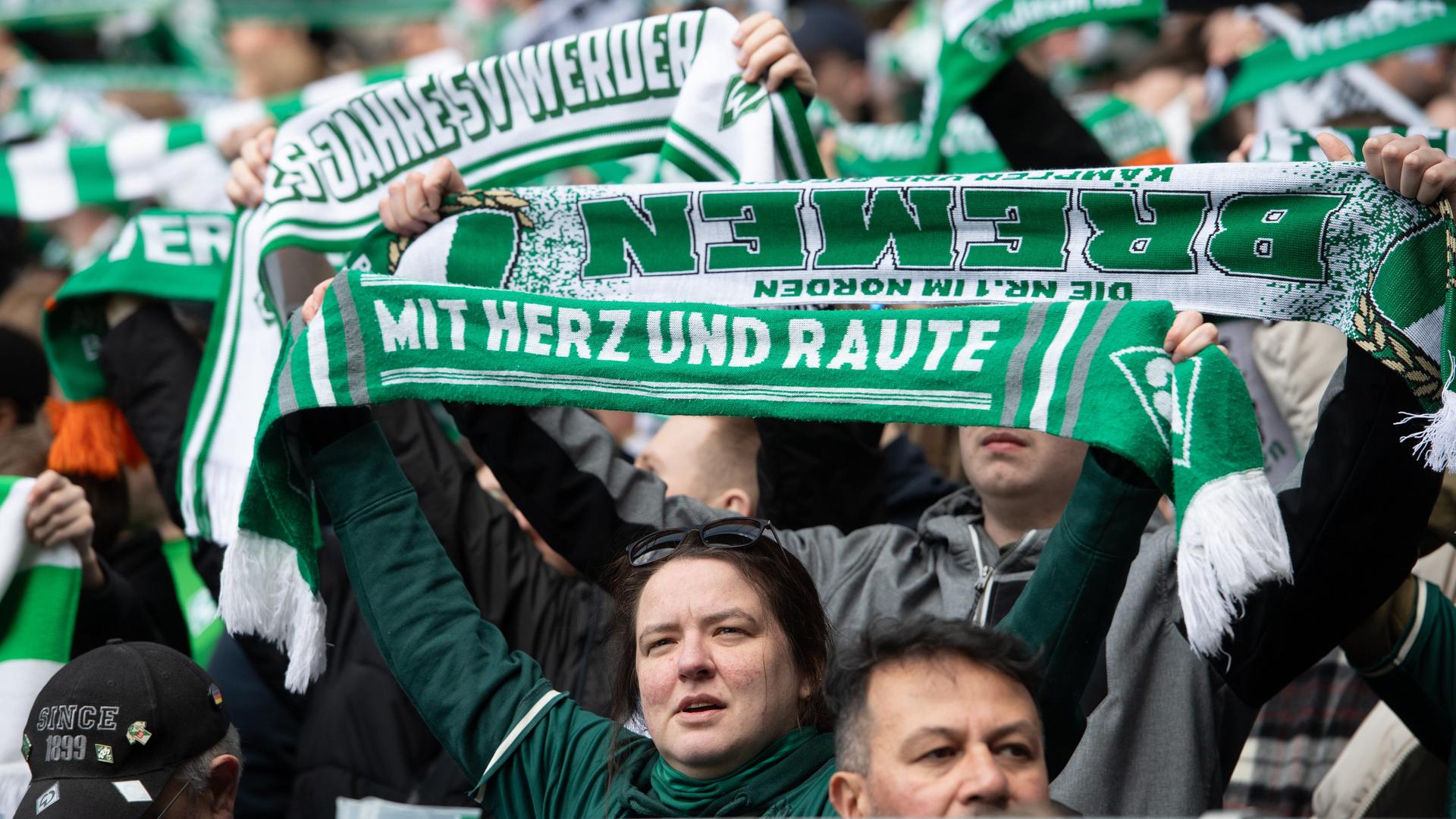 Fans von Werder Bremen mit ihren Schals auf denen "Mit Herz und Raute" steht
