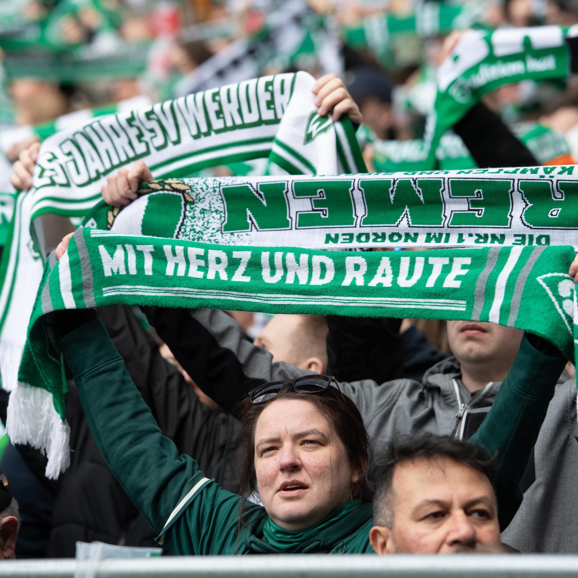 Fans von Werder Bremen mit ihren Schals auf denen "Mit Herz und Raute" steht