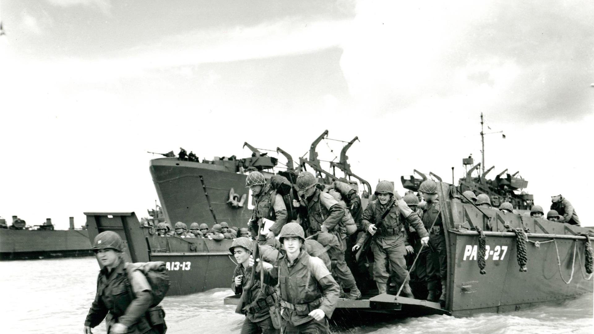 Schwarz-weiß Foto: US-Truppen gehen von einem Landungsboot der US-Küstenwache an Land. 