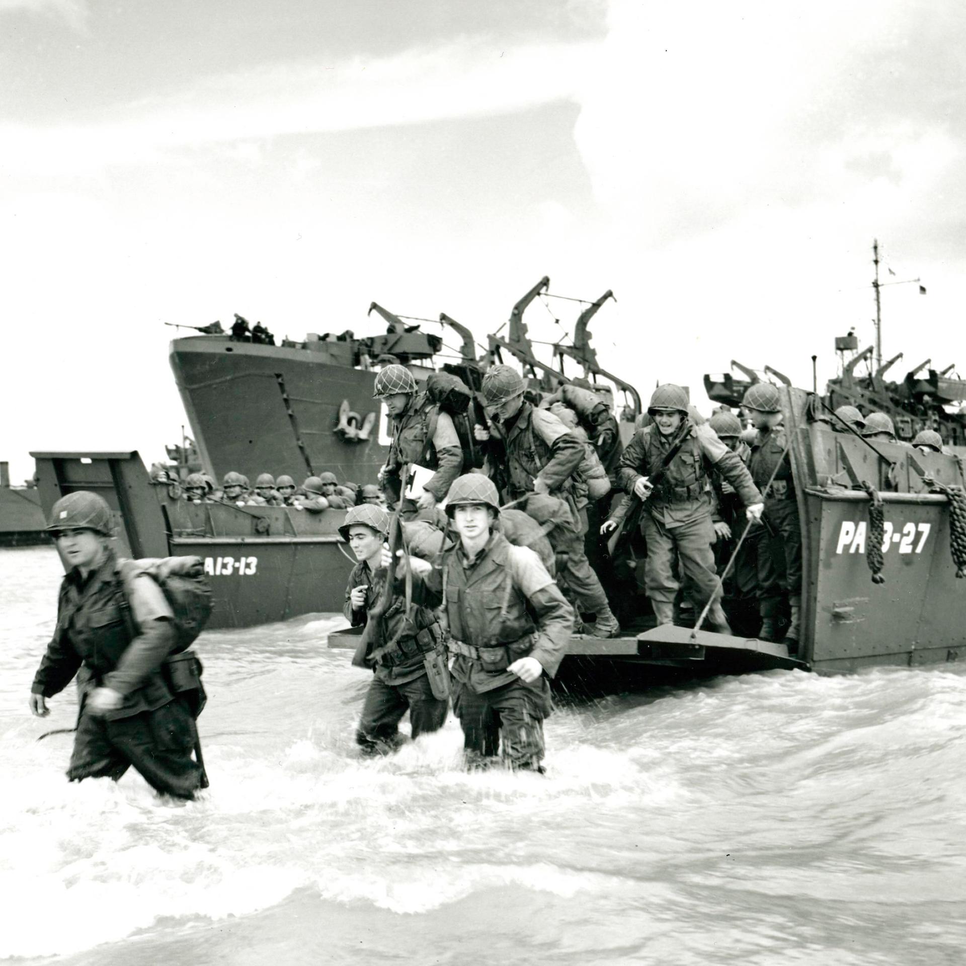 Schwarz-weiß Foto: US-Truppen gehen von einem Landungsboot der US-Küstenwache an Land. 