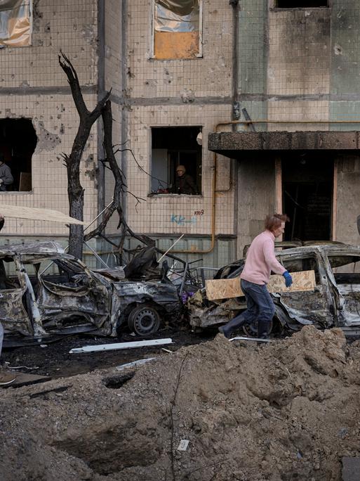 Menschen in Kiew tragen Holzbretter, um die Fenster eines Gebäudes abzudecken, das am Vortag bei einem Bombenangriff beschädigt wurde.