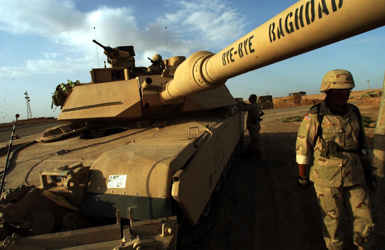 Ein US-Panzer steht in karger irakischer Wüstenlandschaft. Auf dem Lauf steht "Bye Bye Bagdad".